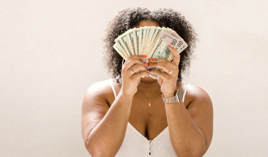 Financial minimalism: Woman holding up a fan of cash