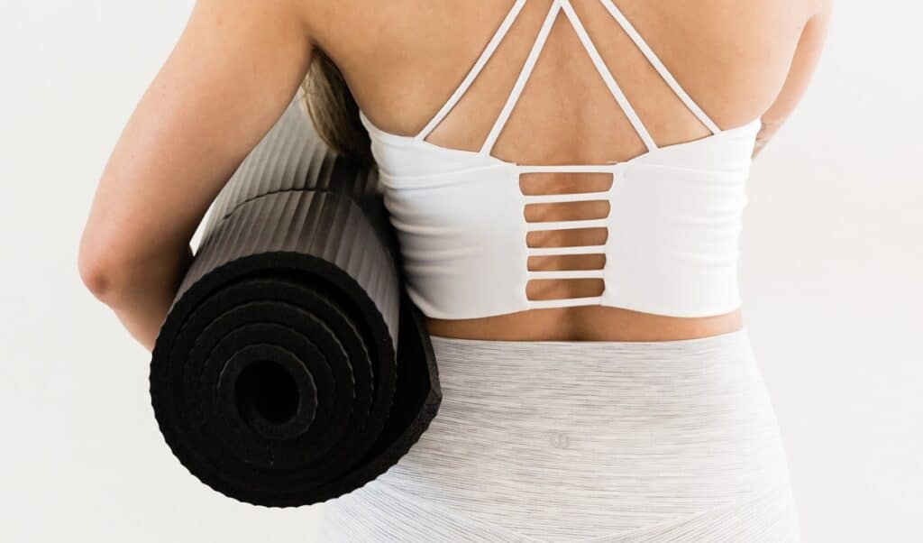 Woman carrying black yoga mat