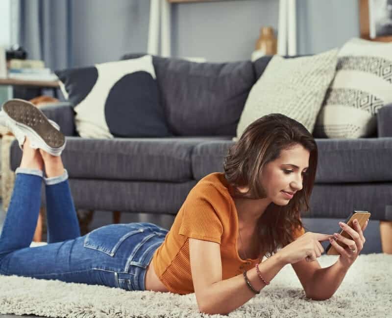 Things that waste your time: woman lying on floor scrolling through social media