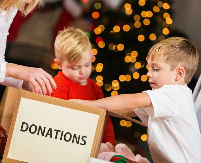 Minimalist Christmas: children putting gifts into donation box