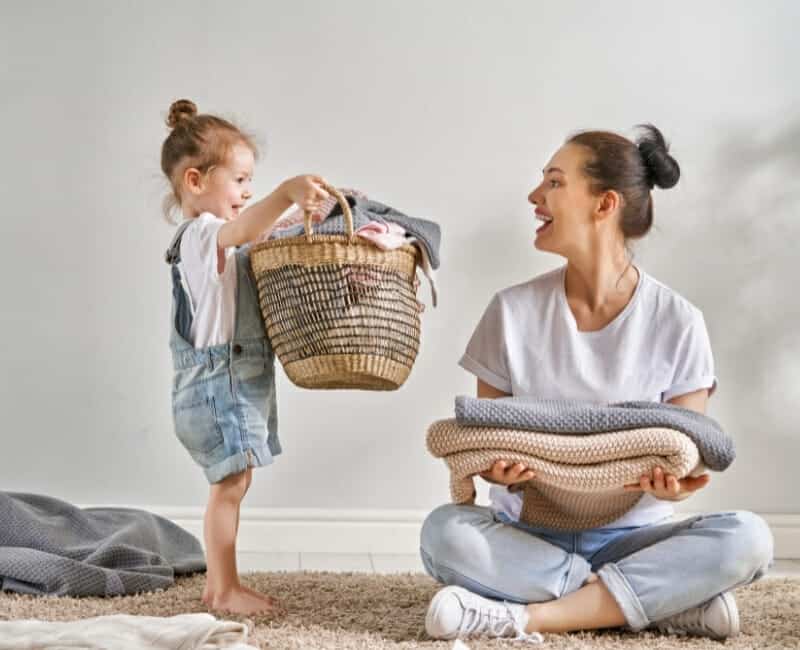 Overwhelmed by laundry: child helping her mother with laundry