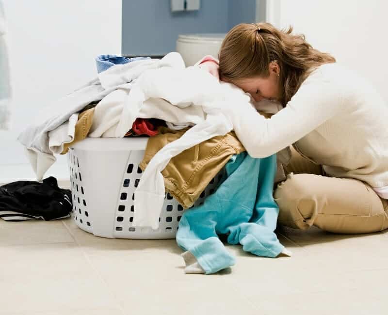 Overwhelmed by laundry: woman hunched over pile of laundry