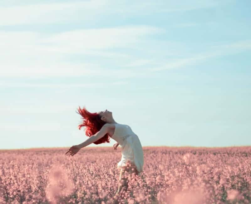Choosing to live with less, woman dancing in field