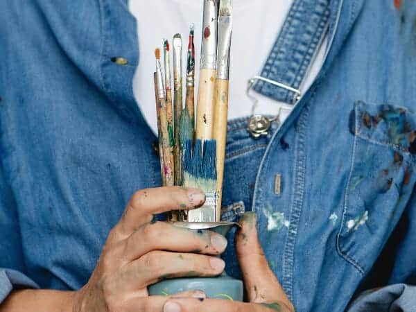 How to declutter craft supplies: woman holding paint brushes