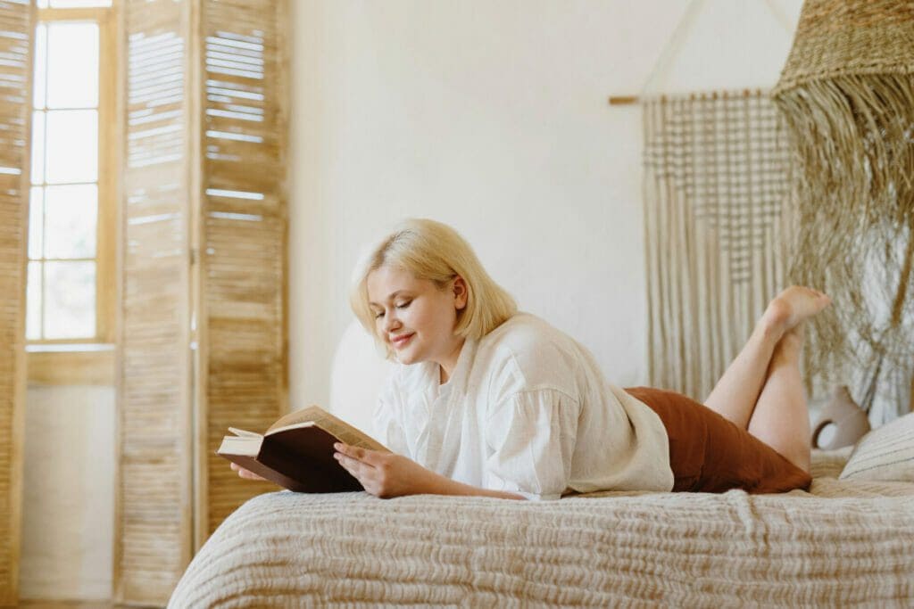 Woman reading a book lying on the bed