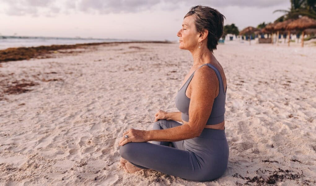 How to slow down: Woman meditating on beach